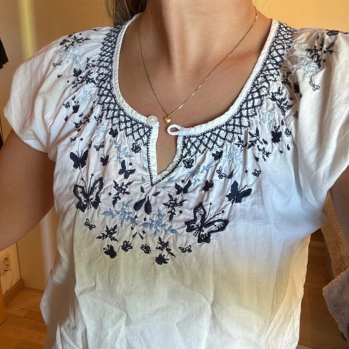 vit blus med blått broderi