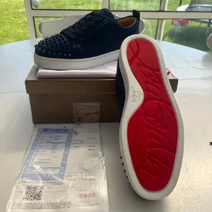 Mörkblå Christian Louboutin sneakers - Säljer ett par mörkblå sneakers från Christian Louboutin med ikoniska röda sulor och svarta nitar på tån🙌🏻 har aldrig använt skorna då de är för små. Längden på innersulan är 28cm