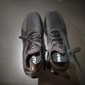 Nike Air Max 270 helsvarta sneakers 38,5 - Säljer ett par helsvarta Nike Air Max 270 sneakers med snygg, chunky sula och diskret logga på sidan. Ovandelen är i mesh och syntet för bra andningsförmåga och komfort. Klassisk snörning och tydlig Air-dämpning i hälen för extra skön känsla.