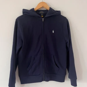 Marinblå hoodie från Polo Ralph Lauren - Snygg marinblå hoodie från Polo Ralph Lauren med dragkedja. Nästan oanvänd. Passar mig som har xs/s vanligtvis. 
