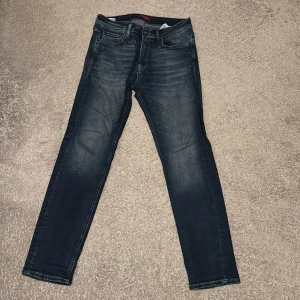 Mörkblå jeans från Jack & Jones - Snygga mörkblå jeans från Jack & Jones med klassisk femficksdesign och diskret slitning på framsidan. Modellen har rak passform och normal midja, perfekt för dig som gillar stilrena och bekväma jeans. Materialet är slitstarkt denim i bomull.