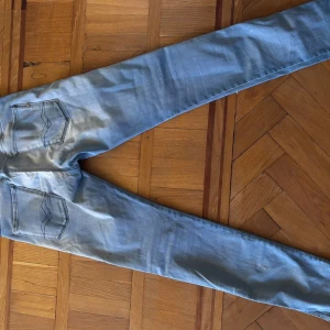Replay ljusblå jeans, storlek 31/32 - Säljer ett par ljusblå jeans från Replay med klassisk femficksdesign och snygga detaljer på bakfickorna. Jeansen har raka ben och normal passform, tillverkade i mjukt jeanstyg som är skönt att bära. Perfekt för dig som gillar stilrena och tidlösa jeans.