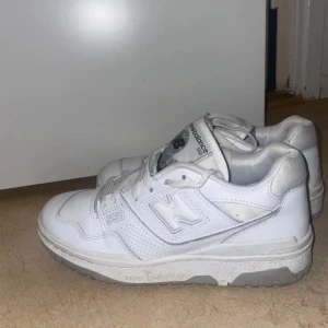 Vita New Balance 550 sneakers - Säljer ett par fräscha vita New Balance 550 sneakers med klassisk siluett och låg profil. Skorna har snörning, platt sula och detaljer i grått. Perfekta för dig som gillar stilrena och sportiga sneakers med retrovibe. Använt dom 3 gånger 