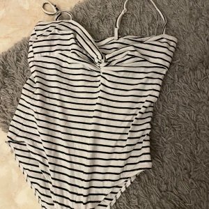 Randig body från Sinsay, S - Supersnygg randig body från Sinsay i vitt och svart. Den har smala axelband och en twistad detalj framtill som ger en extra touch. Materialet känns mjukt och bekvämt mot huden.