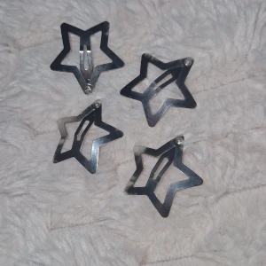 Hårspännen - Fyra stycken stjärnformade hårspännen i blankt silverfärgat metallmaterial. Perfekta för att ge din frisyr en cool och glittrig touch. Hårspännen är lätta att använda och sitter snyggt i håret, passar både till vardagslooken och när du vill sticka ut lite extra.