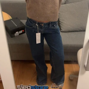 Ultra low wide jeans blå strl 36 - Säljer ett par blå jeans med ultra låg midja och breda ben. Modellen är 'ultra low wide' och har klassiska fickor både fram och bak. Snygga kontrastsömmar och riktigt skön passform för dig som gillar loose och wide jeans.