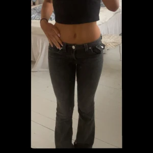 True Religion grå bootcut jeans - Snygga grå jeans från True Religion med bootcut passform och klassiska detaljer som markerade sömmar och ikonisk ficka med lock och knapp bak. Jeansens model är ”Becca Mid Rise” och är tillverkade i mjukt denim-material för en skön känsla.