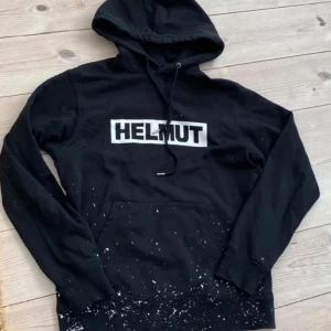 Helmut Lang hoodie - Säljer min svarta Helmut Lang-hoodie med färgstänk då den inte längre används. Den är i mycket fint skick och har en snygg. Den är  unik och  passar till de flesta outfits och stilar. Hör gärna av dig om du har frågor!