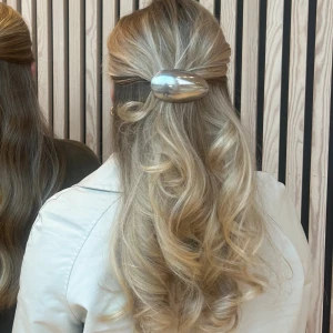 silverfärgad hårklämma - Säljer en oval hårklämma i blank silverfärg som ger en cool och modern vibe till din frisyr. Perfekt för att hålla halva håret uppe och skapa en snygg look. Klämman är gjord av återvunna skedar och återvunnet tyg. 
