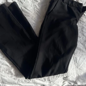 Svarta kostymbyxor från Bik Bok - Svarta kostymbyxor från Bik Bok i klassisk rak modell med dragkedja och knapp framtill. Byxorna har en stilren look och är tillverkade i ett mjukt tyg som känns skönt mot huden. Perfekt för dig som gillar en clean och enkel stil.