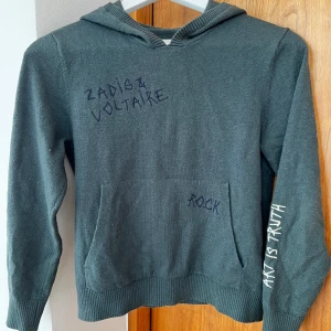 Mörkgrön cashmere hoodie från Zadig & Voltaire - Mörkgrön hoodie från exklusiva Zadig & Voltaire med broderade texter 'ROCK' och 'ART IS TRUTH'. Tröjan har huva och är tillverkad i en mjuk kashmir / merinoull mix Perfekt för dig som gillar en cool och avslappnad stil  Storlek 11 till 12 år.  Nypris 1800 kr Köpt på Lucca på Östermalm 