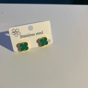 Green-Gold earring  - Snygga örhängen i form av fyrklöver med grön randig yta och guldfärgad kant. Tillverkade i stainless steel, perfekta för dig som vill ha något unikt och stilrent. Små och diskreta men ändå ett statement. Mvh clover.se