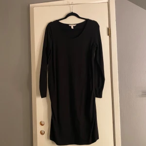 Svart långärmad klänning H&M - En enkel svart klänning från H&M med lång ärm och rundad halsringning. Modellen är rak och slutar strax ovanför knäna, vilket ger en stilren och clean look. Perfekt för dig som gillar minimalistisk stil och vill ha något som funkar till många olika outfits.Den är tagit på!