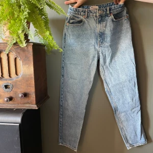 Blå high waist jeans från Zara stl 40 - Snygga ljusblå jeans från Zara med klassisk femficksdesign och hög midja. Jeansen har raka ben och är tillverkade i denim av bomull. Perfekta för en avslappnad och trendig look. OBS! Ett litet hål i grenen, vänligen se bild. 