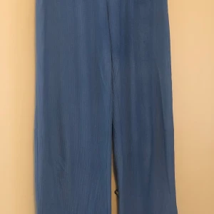 Blå vida linnebyxor - Snygga blå linnebyxor med avslappnad och vid passform. Byxorna har en rak siluett och är tillverkade i ett lätt och luftigt linnematerial, perfekta för en chill och stilren look.