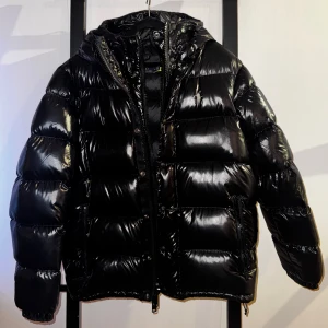 Polo Ralph Lauren, vinterjacka/dunjacka Svart - Säljer en svart pufferjacka från Polo Ralph Lauren med glansig finish och huva.    Jackan är vattenavvisande och har ett extra fodringslager på framsidan. Jackan har broderad logga på bröstet, dragkedja och tryckknappar framtill samt två sidofickor med dragkedja.                                          Perfekt för kalla dagar och riktigt snygg streetstil.                           Nypris 7195kr