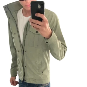 Grön jacka från J.Lindeberg - Snygg grön jacka från J.Lindeberg med dragkedja och knappar framtill. Jackan har långa ärmar och två bröstfickor med knappar. Perfekt för vår och höst 🍂 Skriv för mer info ℹ️, bilder eller funderingar🤩