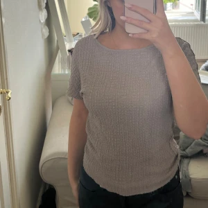 Beige ribbad blus med kort ärm - Säljer en beige blus med ribbad struktur och korta ärmar. Toppen har en rund halsringning och är tillverkad i ett mjukt, stretchigt material som sitter bekvämt. Perfekt för dig som gillar en enkel men snygg look.