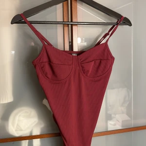 Vinröd ribbad body - Säljer en vinröd body från shein i storlek XS. Baddräkten har smala axelband, bygelinspirerad kupa och är ribbad i materialet. 