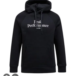 Svart hoodie från Peak Performance - Svart hoodie från Peak Performance med vit broderad logga på bröstet. Klassisk känguruficka, snörning i huvan och mjuk bomullsblandning. Perfekt för en chill och sportig stil.