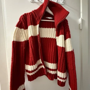 Rödvit randig stickad kofta - Säljer en chunky stickad kofta från Zara i rött och vitt med breda ränder. Koftan har dragkedja framtill, hög krage och långa ärmar. Perfekt för både kalla dagar och sommarkvällar🌟🌟🌟