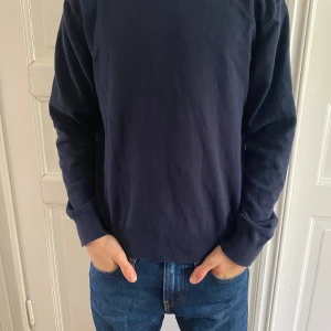 Mörkblå hoodie från Grunt XL - Säljer en stilren mörkblå hoodie från Grunt i storlek XL inom barnstorlekar. Tröjan har huva och passar perfekt för dig som gillar en enkel och clean look. Materialet känns mjukt och skönt mot huden.