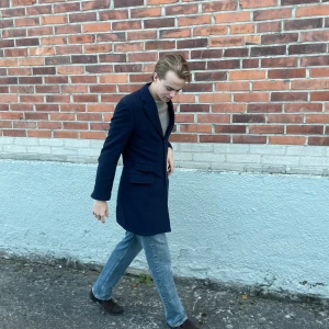 These Glory Days rock - Säljer en stilren mörkblå rock med klassisk krage och knäppning framtill. Jackan har två fickor med lock och en slits bak för extra rörelsefrihet. Perfekt för dig som vill ha en clean och tidlös look.