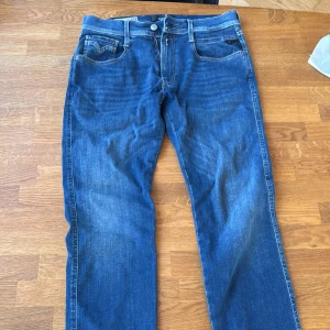 Blå Replay jeans straight fit - Säljer ett par klassiska blå jeans från Replay med raka ben och snygga kontrastsömmar. Jeansen har fem fickor, normal midja och ett stilrent läderpatch bak i midjan. Perfekta för dig som gillar en tidlös look och schysst passform. Defekt bild 4 annars nyskick