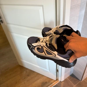 CD B30 - Chunky sneakers från CD med cool design i svart, grått och vitt. Ovandel i mesh och syntet med kontrasterande detaljer och snörning. Grov svart sula ger en sportig vibe och extra höjd. Perfekta för dig som gillar statement-sneakers med streetkänsla.