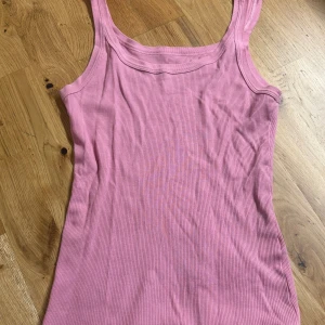 Rosa ribbat linne från intimissimi - Säljer ett rosa ribbat linne från intimissimi. Linnet har en klassisk, ärmlös design med breda axelband och rundad halsringning. Materialet är mjukt och stretchigt, perfekt för varma dagar eller lager på lager. Enkel och stilren modell som är lätt att matcha.