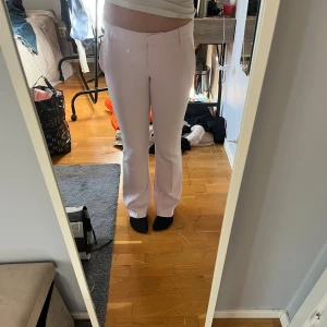 Ljusrosa kostymbyxor från BikBok - Snygga ljusrosa kostymbyxor från BikBok i storlek 34. Byxorna har raka ben med lätt bootcut, hällor för bälte och dekorativa bakfickor. Perfekt för dig som vill ha en clean och fräsch look med lite färg.