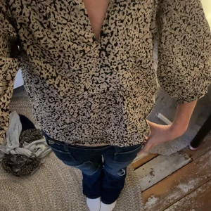Beige och svart blus från Lindex XS - Säljer en luftig blus från Lindex i storlek XS. Blusen är beige med svart leopardmönster, har v-ringning och trekvartsärmar med lätt puff. Materialet känns mjukt och flowy, perfekt för dig som gillar en avslappnad men trendig stil.💗💗