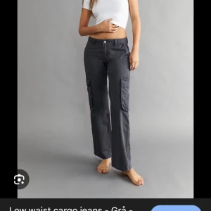 Gråa cargobyxor med låg midja - Säljer ett par grå cargobyxor med låg midja och raka ben. Byxorna har stora fickor på sidorna och klassisk cargostil. Perfekta för en avslappnad och trendig look. Materialet känns slitstarkt och passar till många olika outfits.