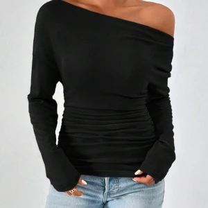 Svart offshoulder topp med rynk - Snygg svart offshoulder topp med lång ärm och rynkade detaljer vid midjan. Toppens stilrena design och figurnära passform gör den till ett riktigt statement-plagg. Mjuk och stretchig, perfekt att matcha med jeans eller kjol för en cool look.