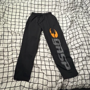 Svarta gymbyxor från GASP - Svarta gymbyxor från GASP med stor logga i grått och orange på ena benet. Byxorna har resår och snörning i midjan för skön passform. Perfekta för gymmet eller chill hemma. Raka ben och mjukt material. Säljer för dom är för små! Storlek S