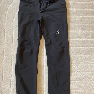 Svarta friluftsbyxor från Haglöfs M - Svarta friluftsbyxor från Haglöfs i storlek M. Byxorna har raka ben, dragkedjor vid fickorna och är tillverkade i ett slitstarkt syntetmaterial. Perfekta för utomhusaktiviteter och äventyr.