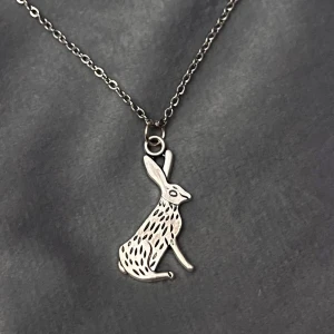 Halsband Hare Silver imitation  - Ett fint halsband i silverimitation med en berlock i form av en hare. (Eller kanin? Men den påminner mer om en hare). Berlocken är ca 1,5 cm hög och 1, 5 cm bred. Halsbandet är justerbart 40-45 cm. 