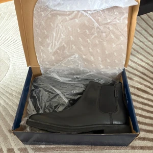  Polo Ralph Lauren Chelsea boots  - Stilrena svarta chelsea boots från Polo Ralph Lauren i skinn. Klassisk design med elastiska paneler på sidorna och rund tå. Perfekta för dig som vill ha en clean och tidlös look. Säljes i originalkartong. Helt nya.