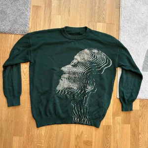 Mörkgrön stickad tröja med grafiskt tryck - Snygg mörkgrön stickad tröja med ett unikt grafiskt tryck i form av ett glitchat ansikte på framsidan. Tröjan har rund halsringning och långa ärmar, sjukt fet passform. Skriv och hör av dig om du har några frågor eller vill diskutera pris 🙏