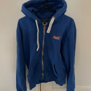 Blå Superdry zip hoodie  - Blå zip hoodie från Superdry i storlek S, modellen är ca 180cm. Hör av dig vid funderingar!
