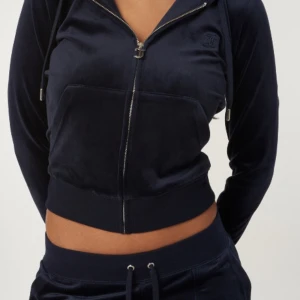 Juicy Couture marinblå velour hoodie - Juicy Couture hoodie i marinblå velour med dragkedja och huva. Tröjan har långa ärmar, ficka framtill och snygg JC-detalj på dragkedjan. Perfekt för en chill och trendig look. Pris kan diskuteras 
