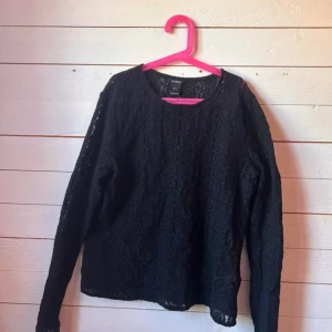 Svart spetsblus från Kappahl - Säljer en svart långärmad blus i spets från Kappahl. Blusen har ett vackert blommigt spetsmönster och rund halsringning. Perfekt för dig som vill ha en stilren men ändå detaljrik topp. Lätt transparent och superfin till jeans eller kjol.