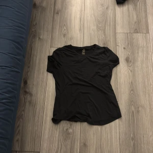 Svart tränings-tshirt från SOC - Svart t-shirt från SOC i sportig modell med rund hals och korta ärmar. Tillverkad i ett lätt och tekniskt material som andas, perfekt för träning. Diskret logga framtill nedtill. Sitter skönt och är enkel att matcha med andra träningskläder.