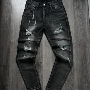 Slim jeans grå - Gåra jeans med slitna och trasiga detaljer framtill, snyggt tvättad look och tapered passform. Klassisk femficksmodell med knapp och dragkedja i midjan. Perfekt för dig som gillar en edgy streetstil.