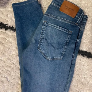 Blå jeans från Jack & Jones - Säljer ett par klassiska blå jeans från Jack & Jones i storlek 27/30. De är insydda lite för en mer tightare och ”grisch” look. Ny pris ~ 1000 kr. | Skriv vid några frågor!