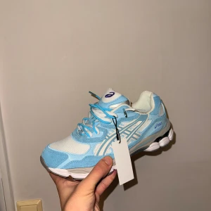 ASICS sneakers i ljusblått och vitt - Helt nya ASICS sneakers i en snygg ljusblå och vit färgkombination. Skorna har mesh och mockadetaljer, dubbel snöring och rund tå. 