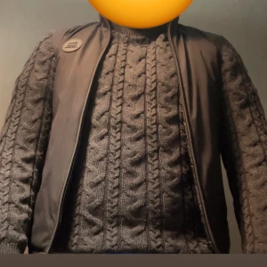 Svart dunväst från Woolrich - Svart dunväst från Woolrich med hög krage och två dragkedjefickor framtill. Västen har en stilren look med diskret logomärke på bröstet och hel dragkedja. Perfekt att slänga över en stickad tröja för extra värme och stil. Endast använt ett fåtal gånger. Priset kan reduceras vid snabb affär ‼️