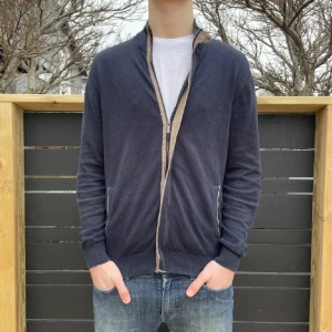 Mörkblå kofta från Massimo dutti - Säljer en stilren mörkblå kofta från Massimo dutti med dragkedja och kontrasterande detaljer i beige. Perfekt för en avslappnad men ändå snygg look. Koftan har långa ärmar och ribbade muddar. Den ger en väldigt exklusiv känsla. Pris kan ändras vid snabb affär!