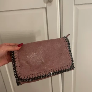 Rosa kuvertväska med kedjedetaljer - Snygg rosa kuvertväska i ÄKTA skinn från Borse in Pelle, tillverkad i Italien köpt i Grekland . Väskan har glansig finish och coola kedjedetaljer. Aldrig använd köpt för 800kr 