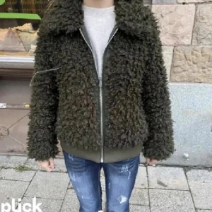 Mörkgrön teddyjacka med dragkedja - Säljer en mörkgrön teddyjacka med fluffig struktur och bred krage. Jackan har hel dragkedja framtill och ribbade muddar vid ärmslut och nederkant. Perfekt för dig som vill ha en mysig och trendig look under kyliga dagar.